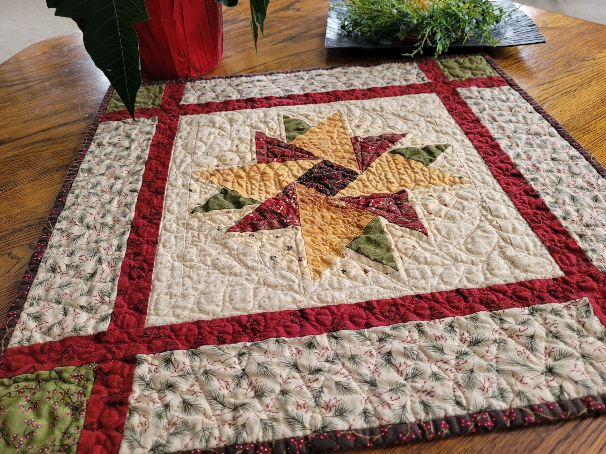 Quilt with star design on a wooden table and holiday decor in the background