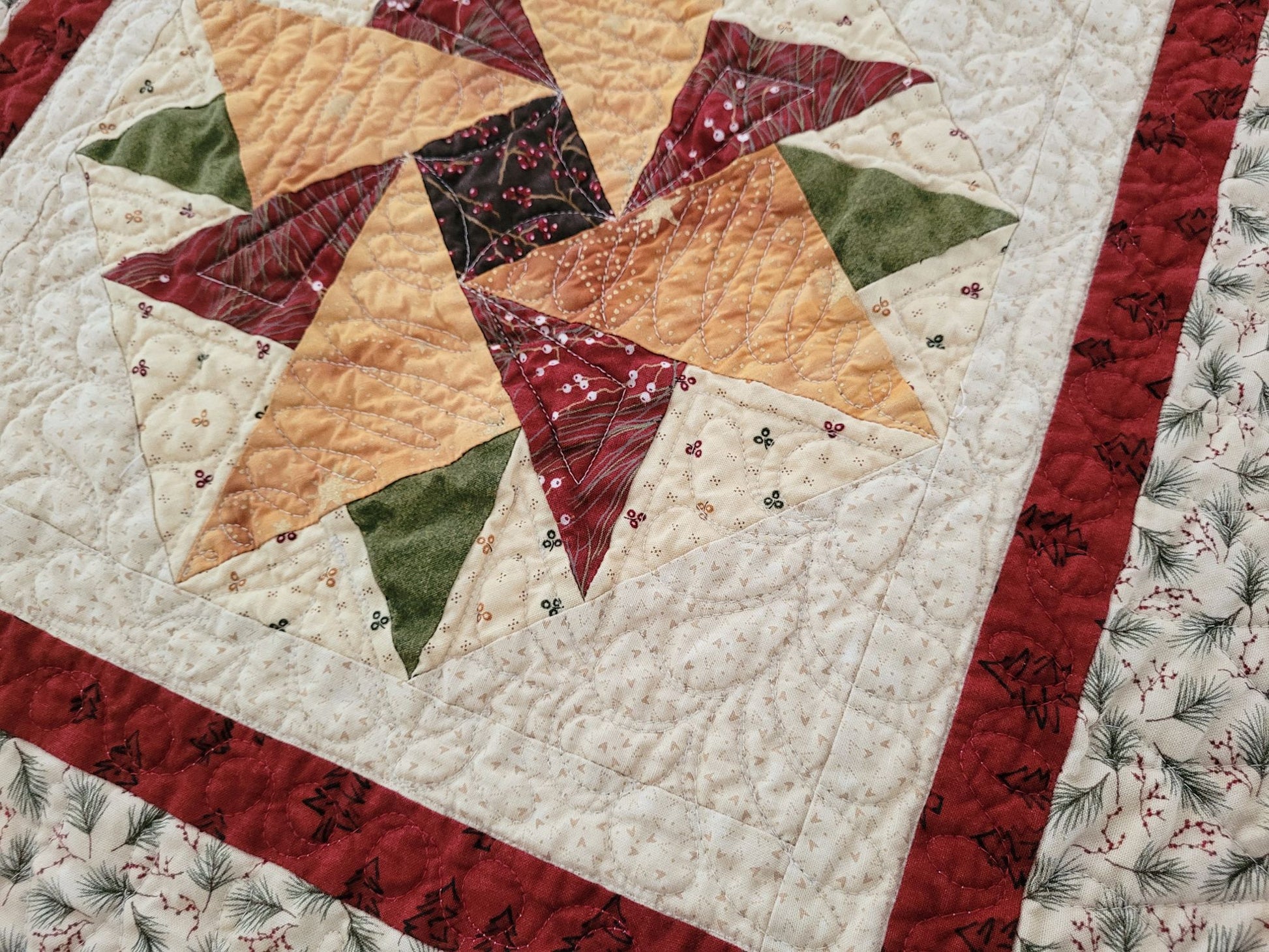 Quilt with star pattern featuring red, green, and gold colours.