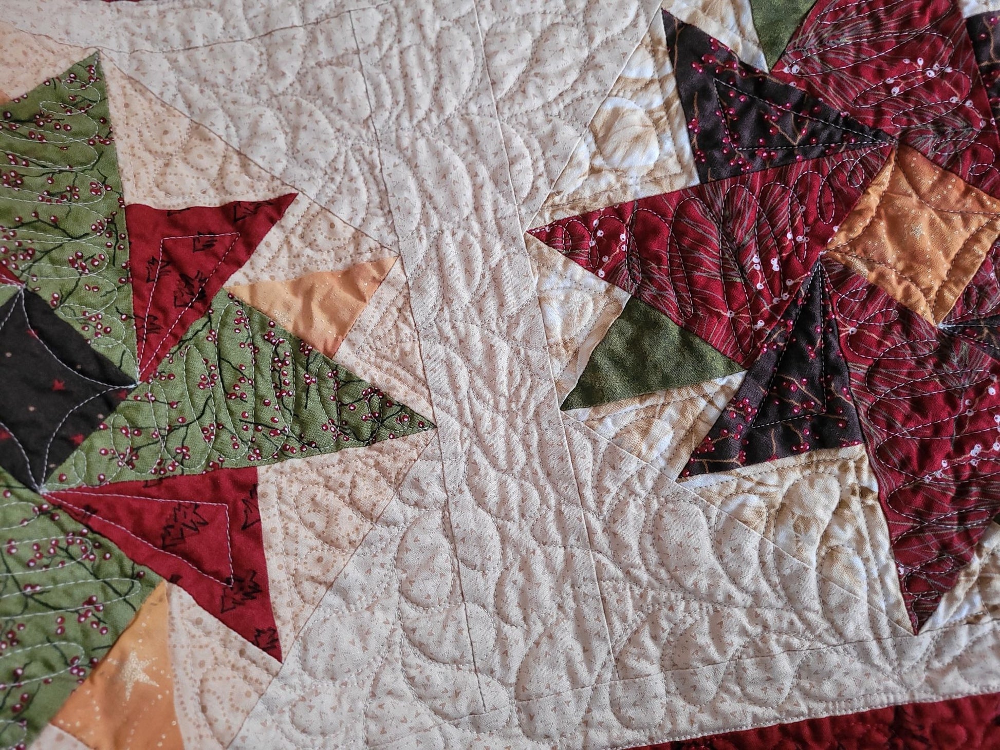 Close-up of a patchwork quilt with star patterns in red, green, gold and beige.