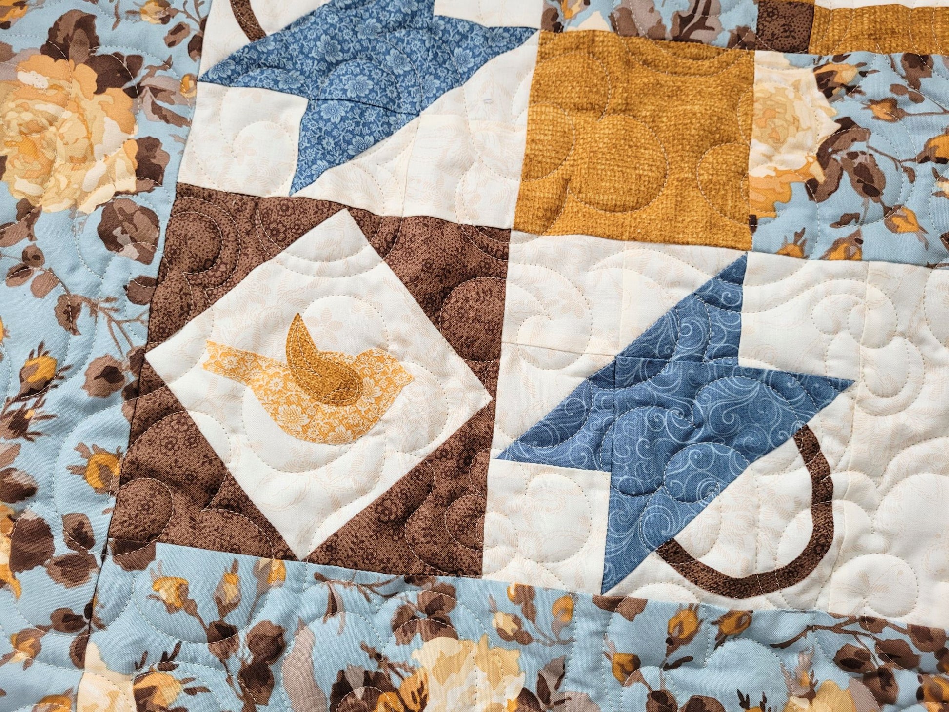 Quilt with birds and patchwork basket patterns and floral designs in brown, blue, gold and white.