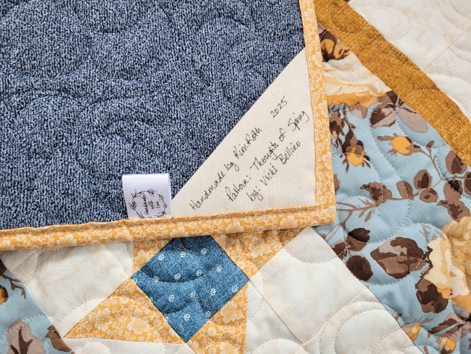 Showing the close-up back of the Thoughts of Spring throw quilt with a handwritten label.