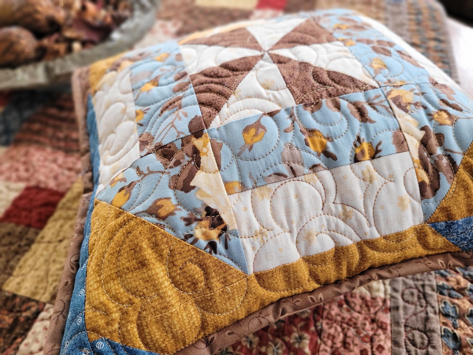 Quilted pillow with patchwork design on a textured fabric background.