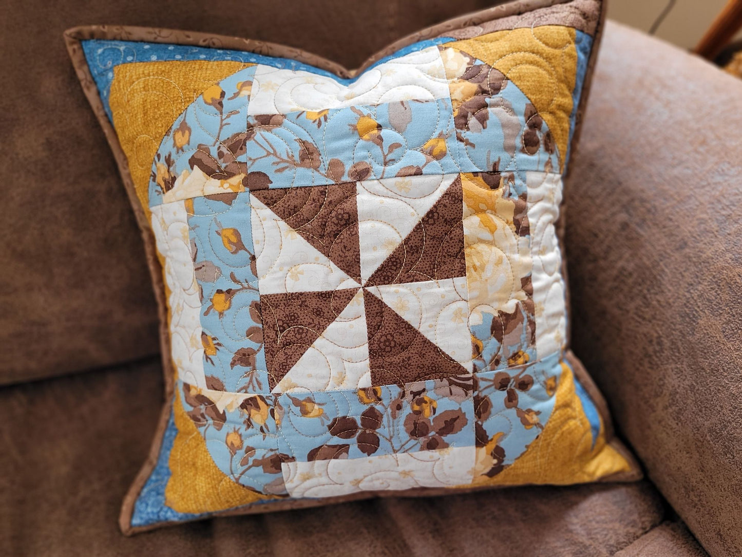 Quilted patchwork pillow on a couch.