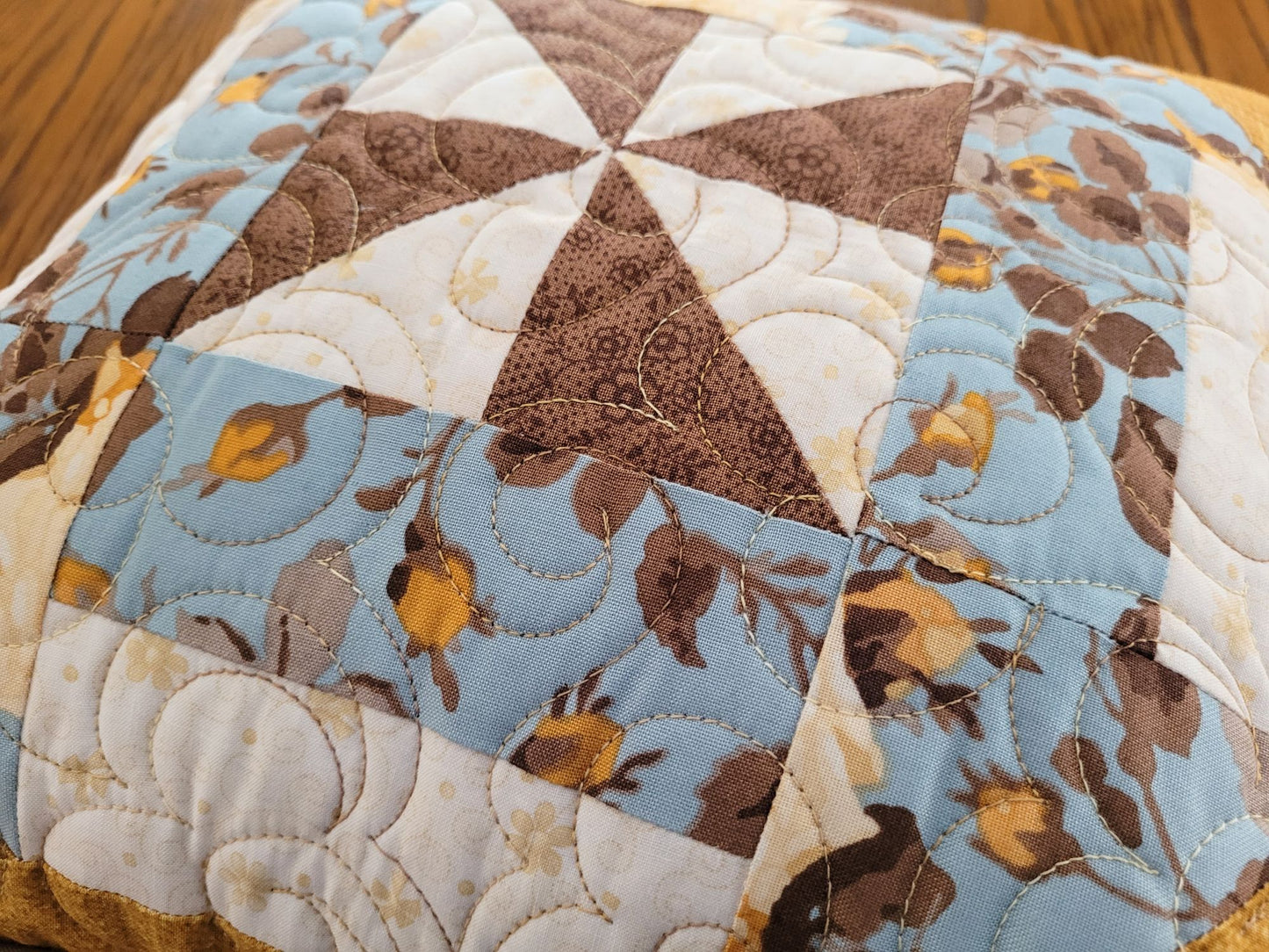 Close-up of the quilted pillow with floral pattern on a wooden surface.