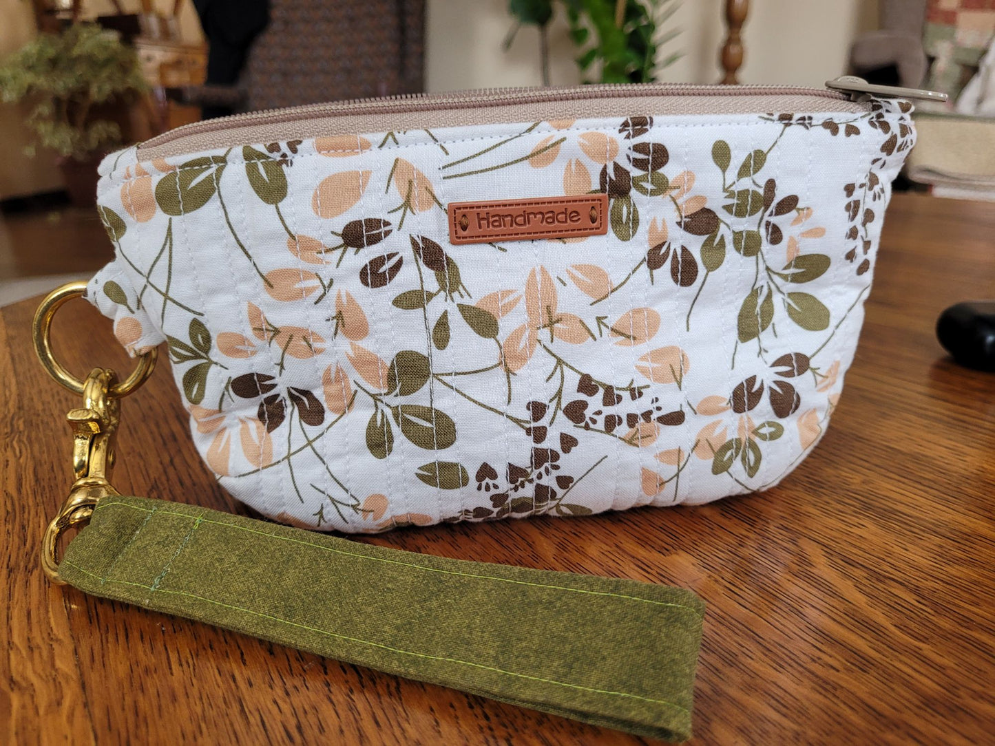 Close up of quilted wrist wallet on a wooden surface in a living room. 