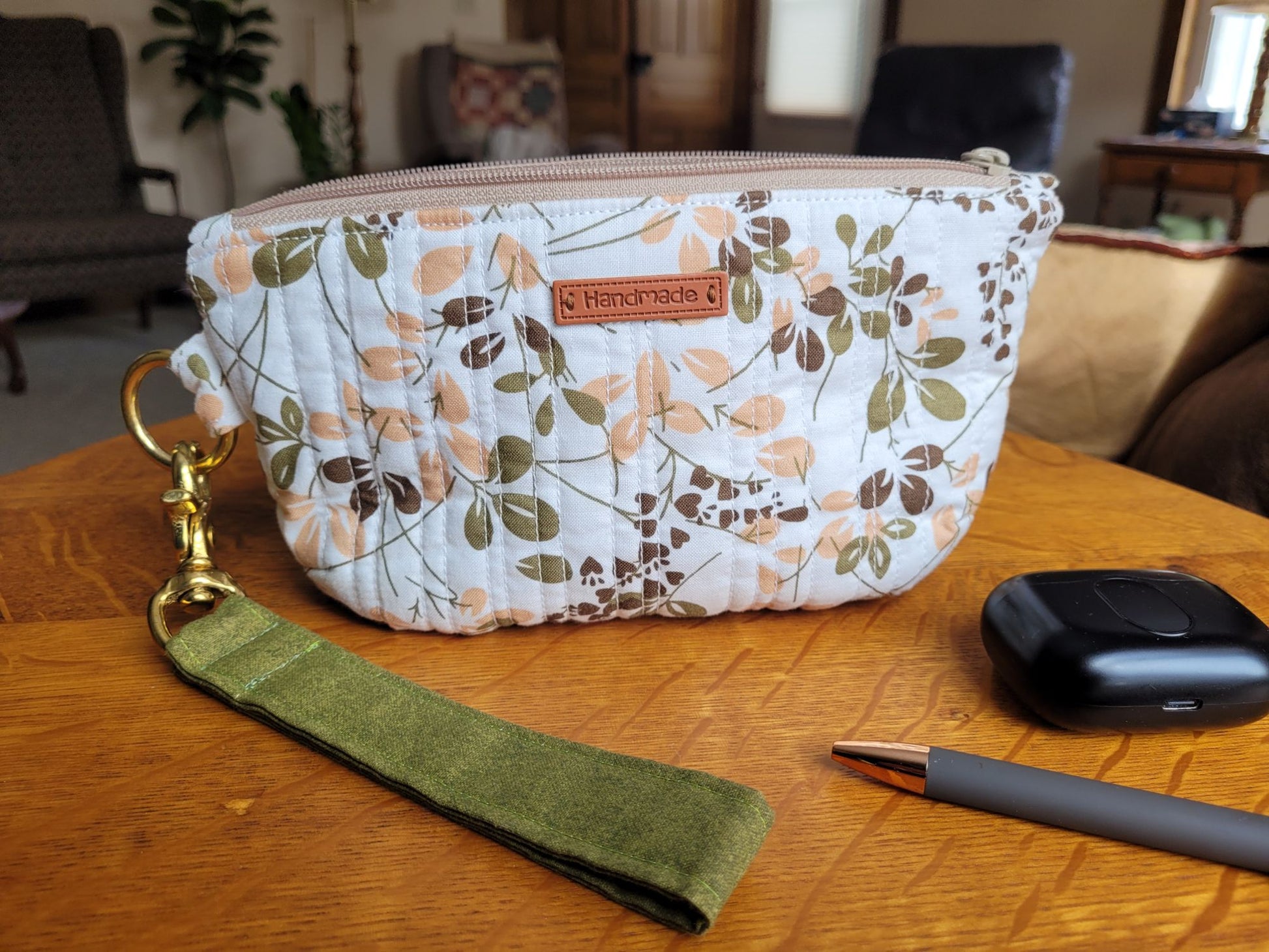 Quilted zipper wrist wallet on wooden surface in a living room. 