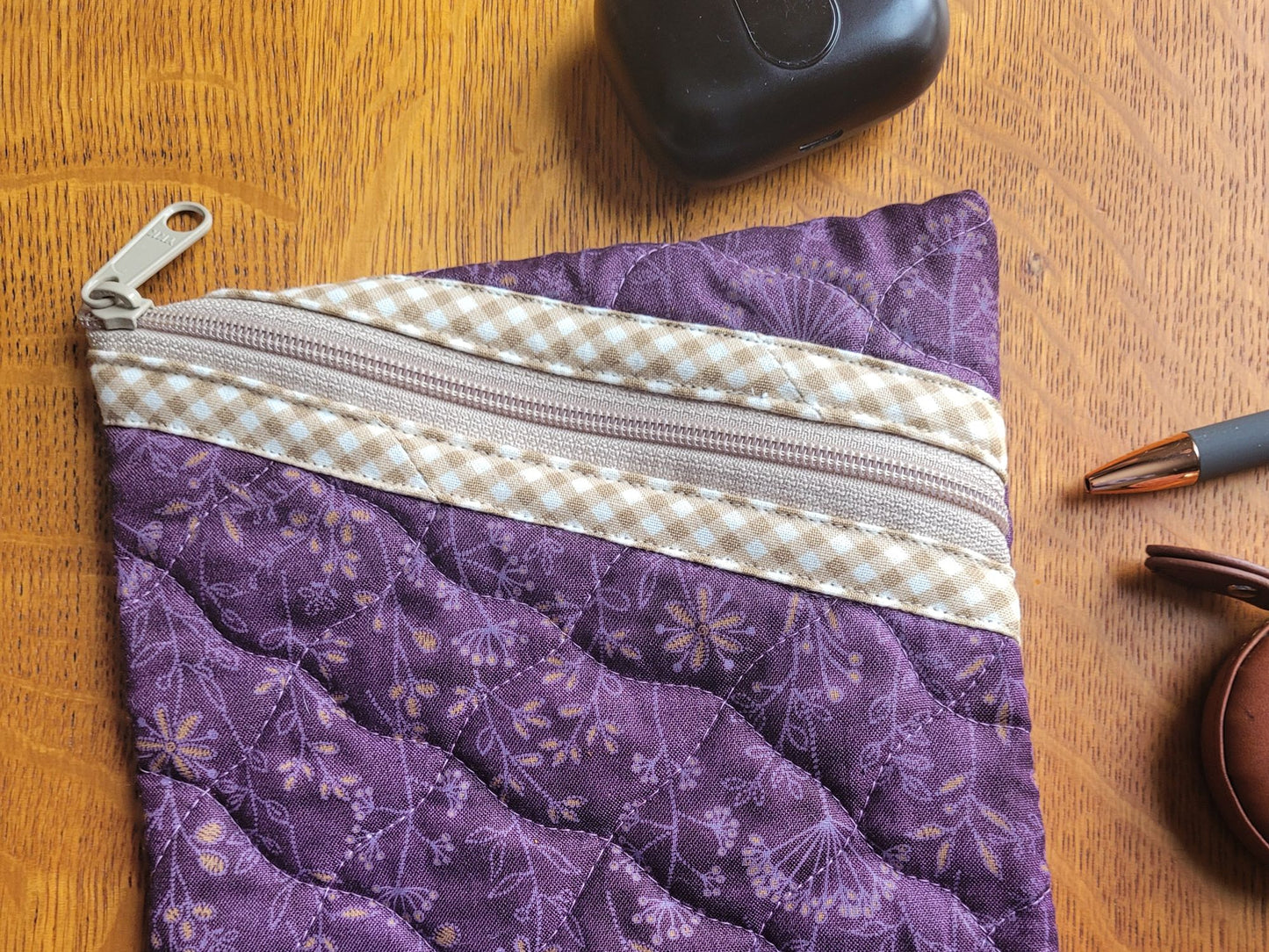 Purple quilted pouch with a zipper on a wooden surface