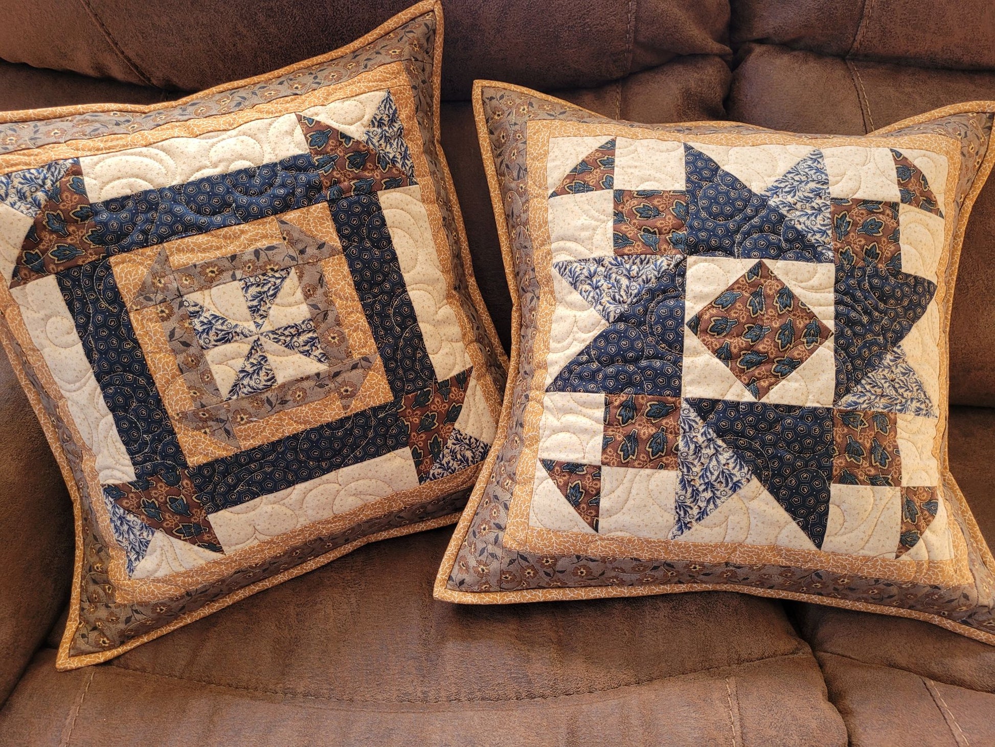 Two decorative pillows with star patterns on a brown sofa.