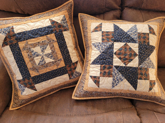 Two decorative pillows with star patterns on a brown sofa.