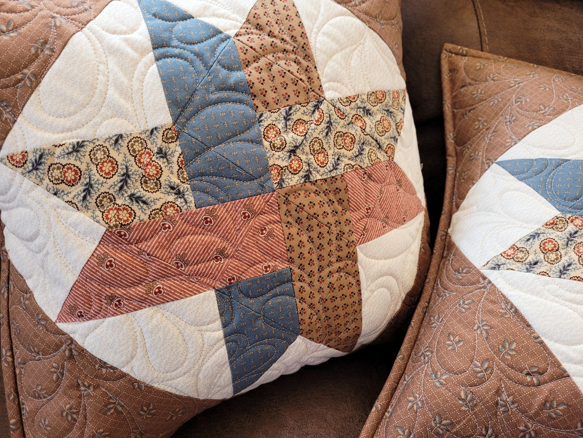 Patchwork quilted pillows with a brown and beige color scheme.