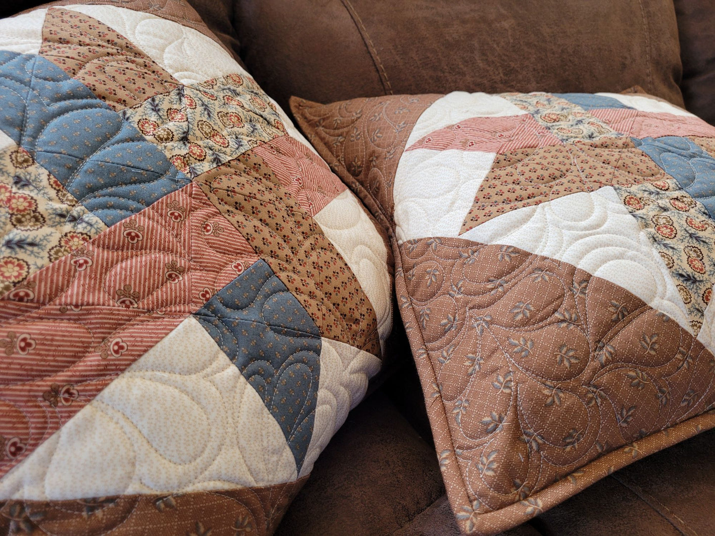 Patchwork quilted pillows on a brown sofa