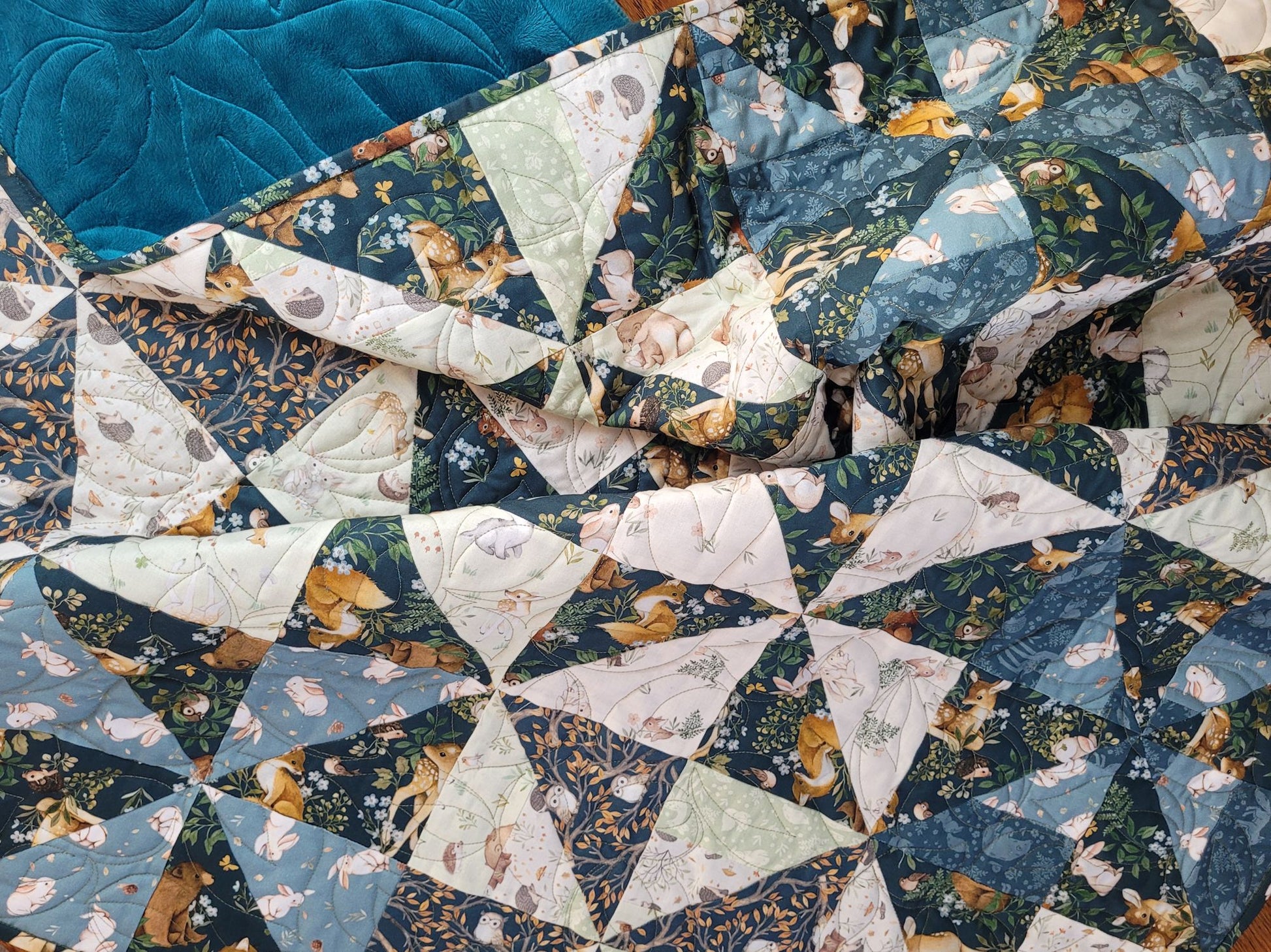 Quilt with a patchwork design featuring triangles in various woodland theme prints in blue and cream.
