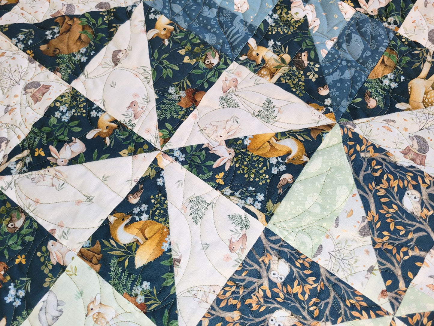 Close up of quilt with triangular fabric pieces featuring animal and nature patterns.