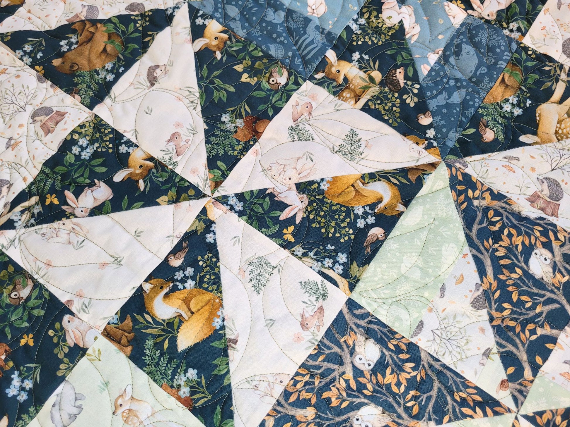 Close up of quilt with triangular fabric pieces featuring animal and nature patterns.