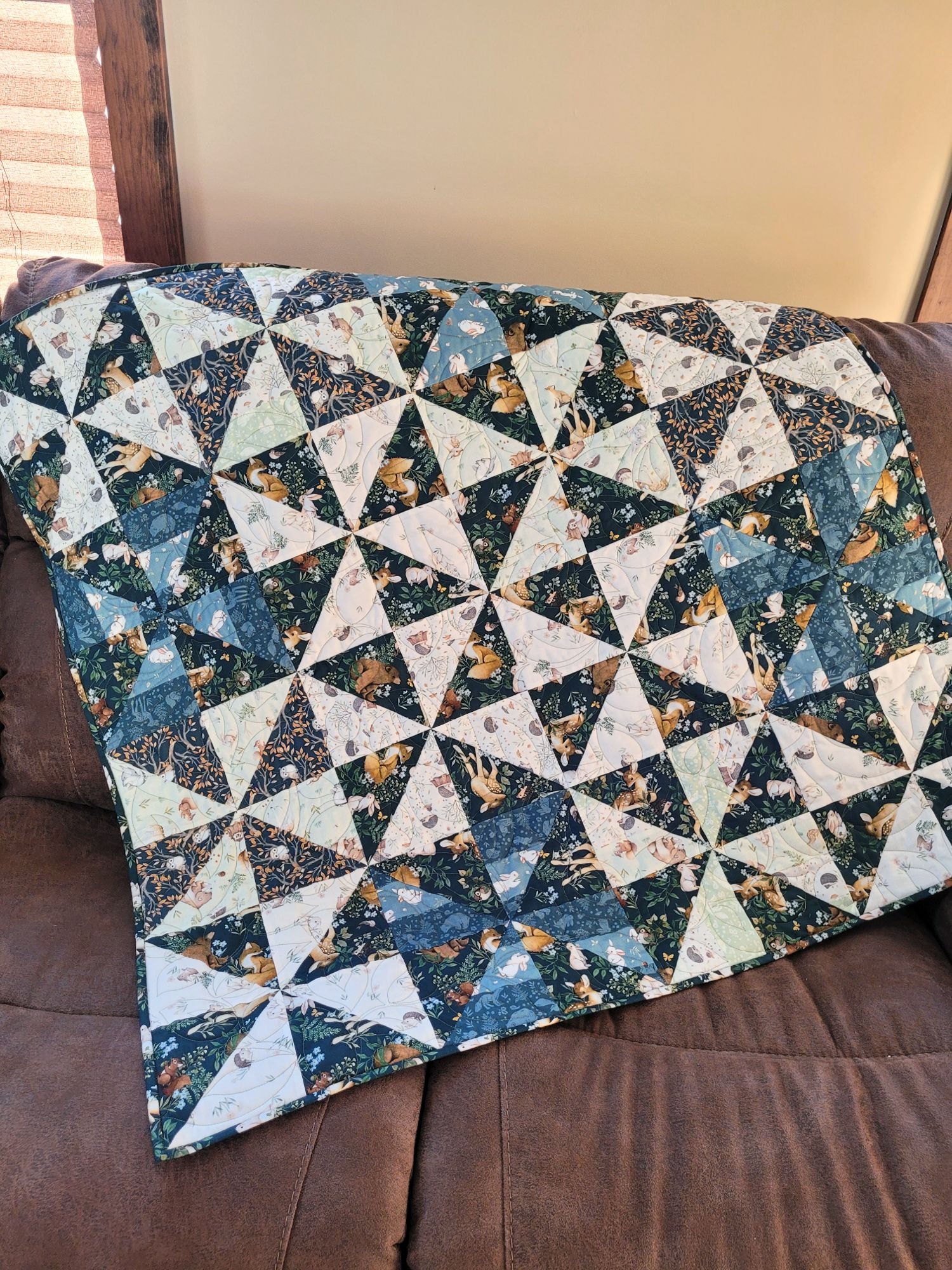 Quilt with a geometric pattern on a brown couch.