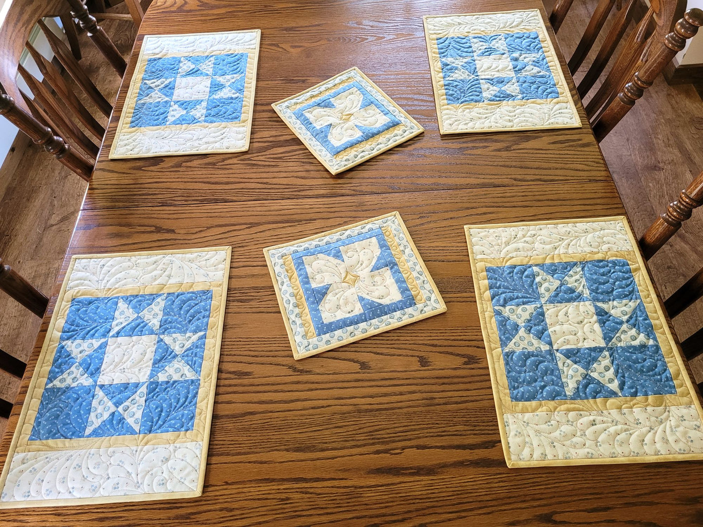 Quilted placemat set with hot mats on a wooden dining table.