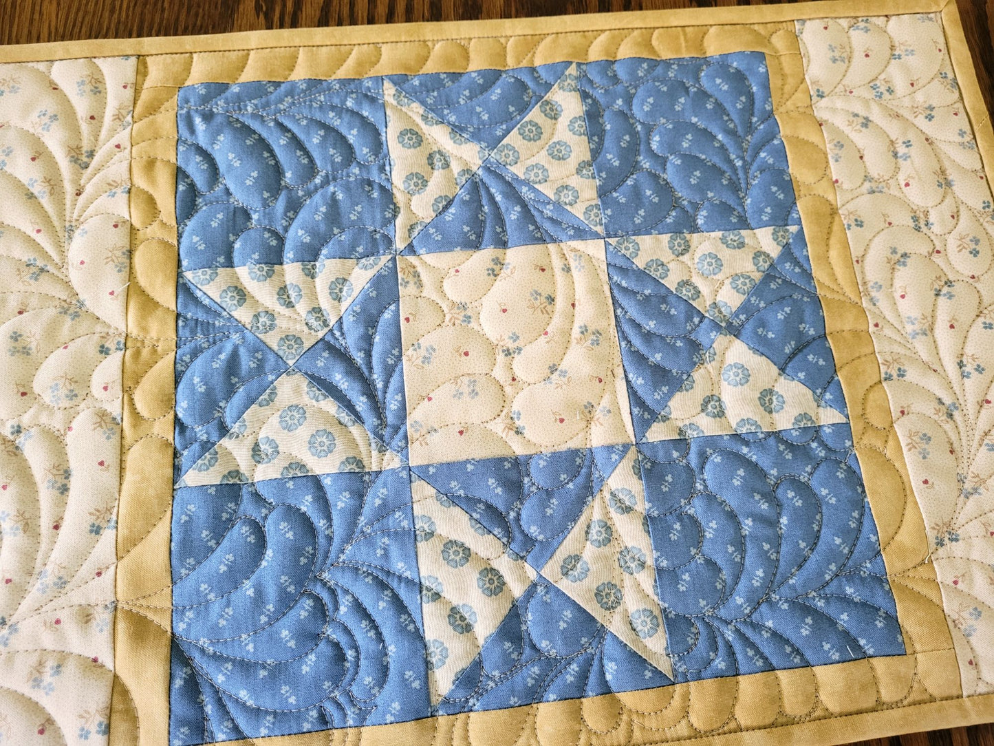 Close up of quilted placemat with patchwork star, showing feather quilting.