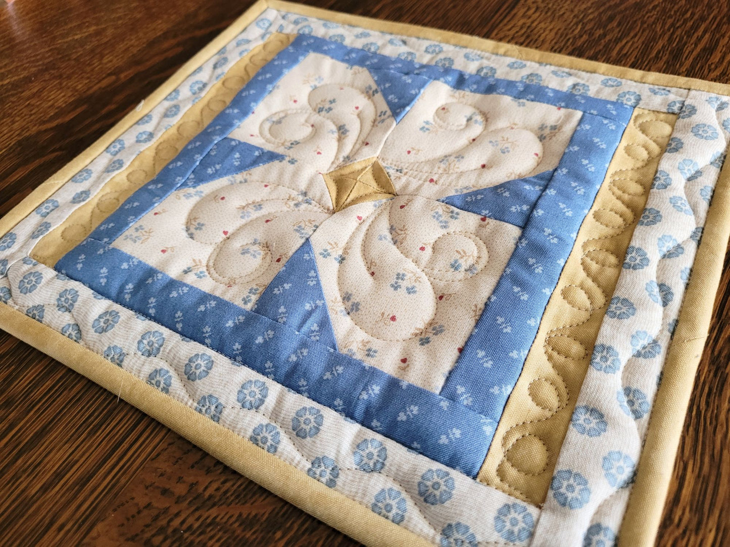 Close up angle view of the quilted hot mat on a wooden table.