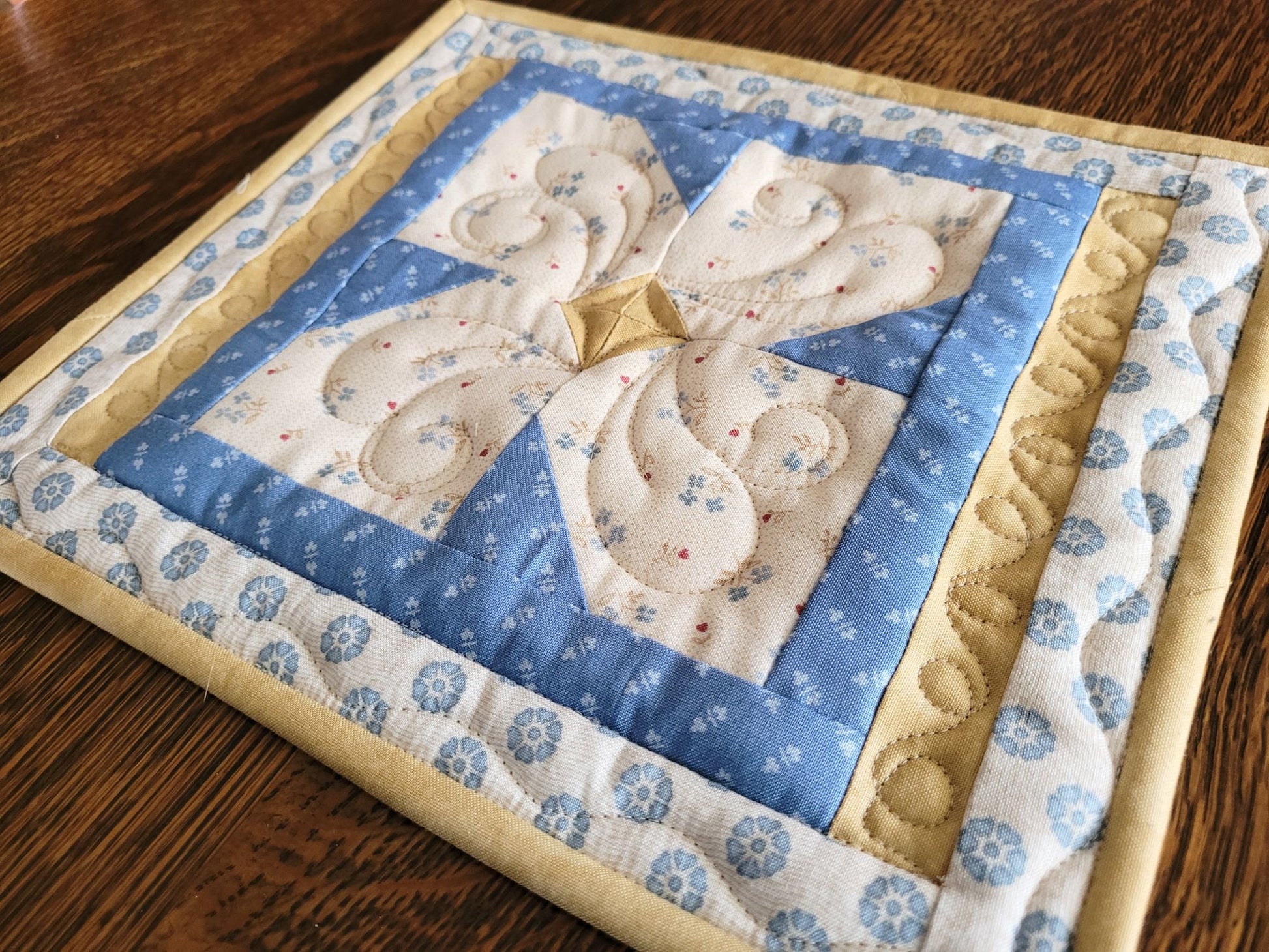 Close up angle view of the quilted hot mat on a wooden table.