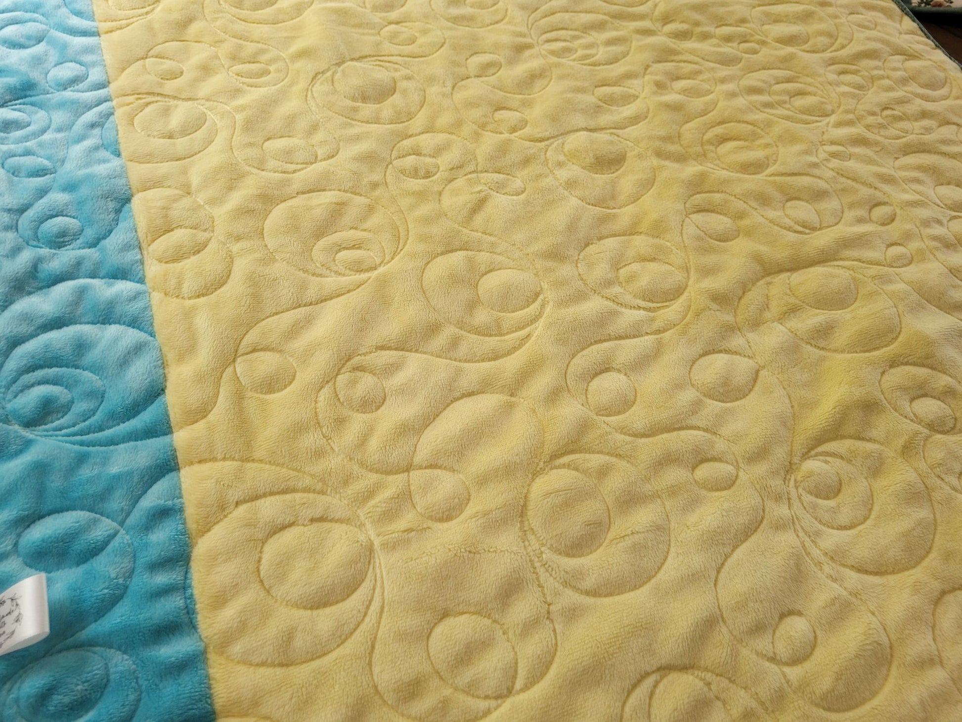 Showing the soft minky back of the baby quilt in yellow with a blue side stripe.