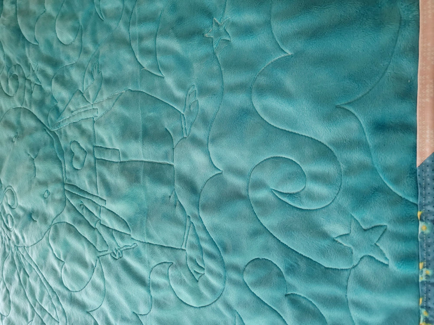 Soft teal back of bunny baby quilt showing stitching texture.