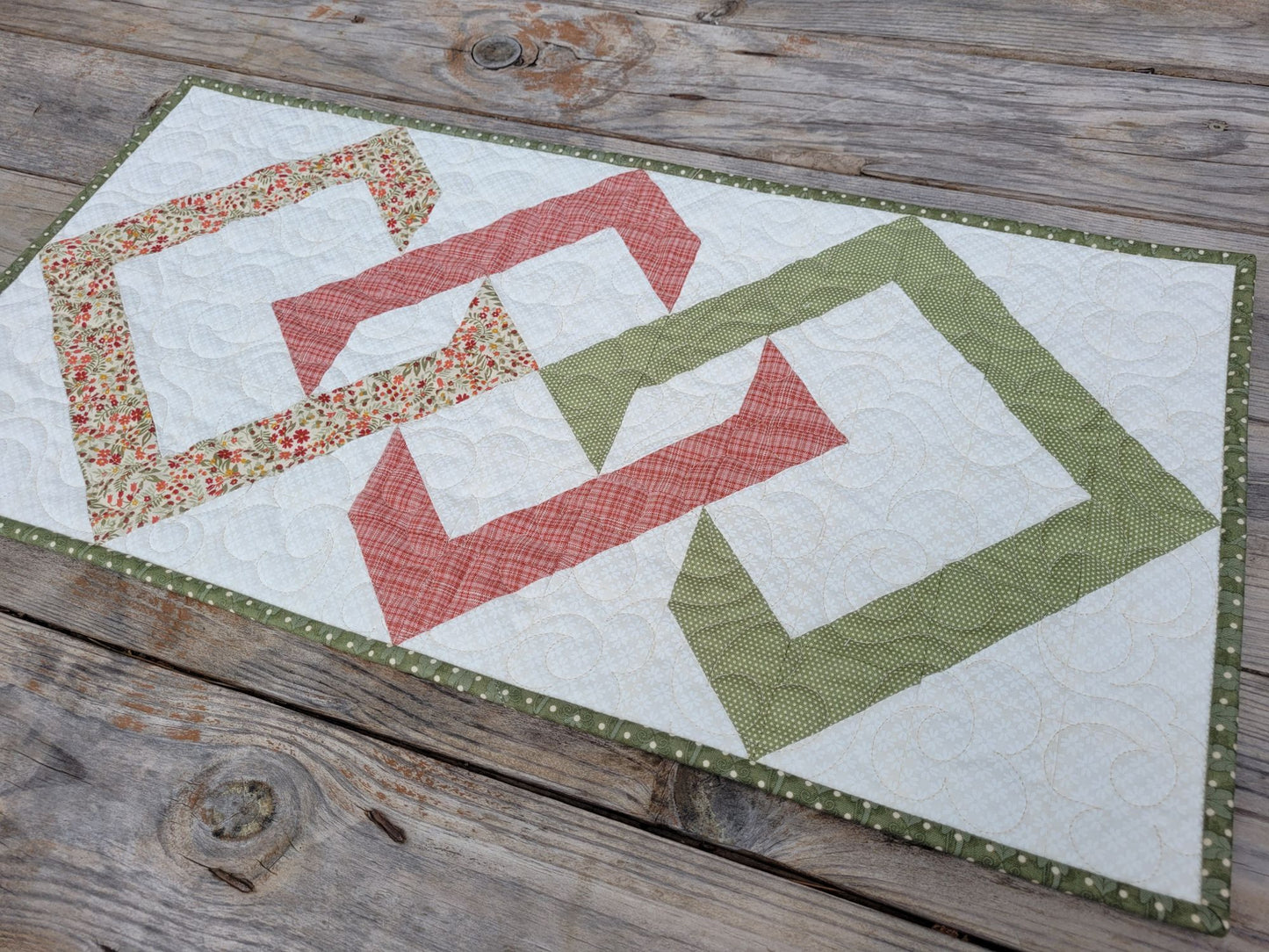 Quilted table runner with geometric pattern on a wooden surface