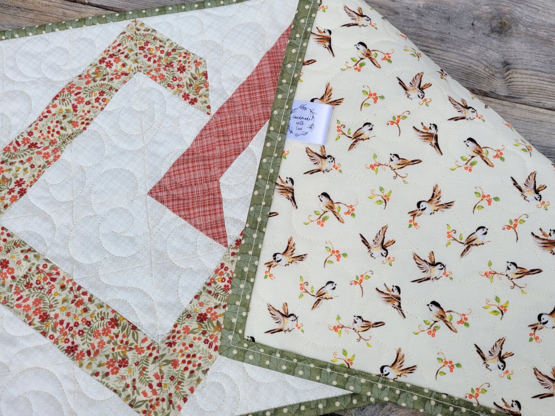 Back of quilted table runner is folded over showing bird fabric and handmade label.
