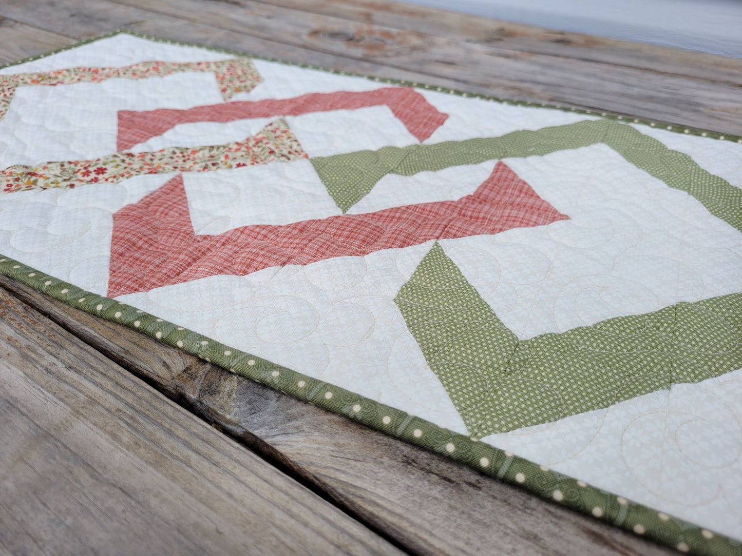 Angle view of quilted table runner on a wooden surface.