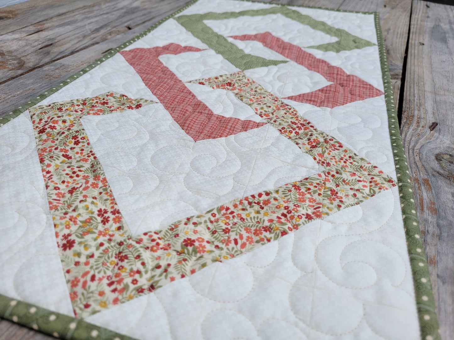 Long angle view of the quilted table runner on a wooden surface.