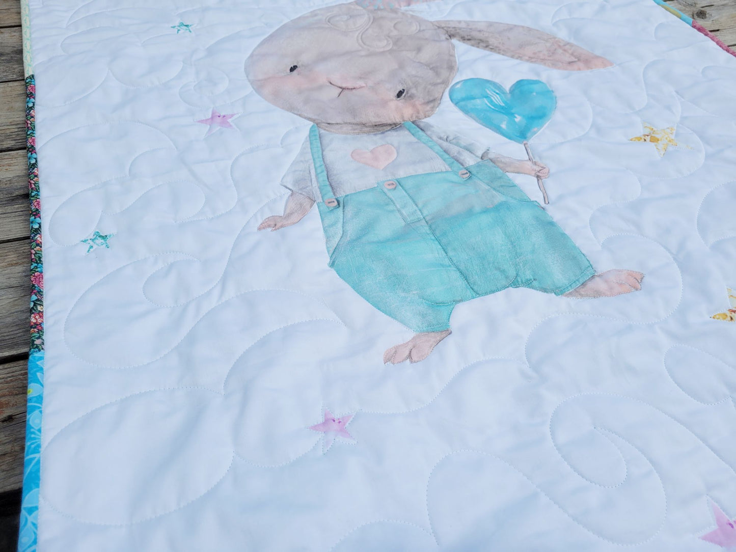 Quilt with a bunny character holding a blue heart balloon on a white background
