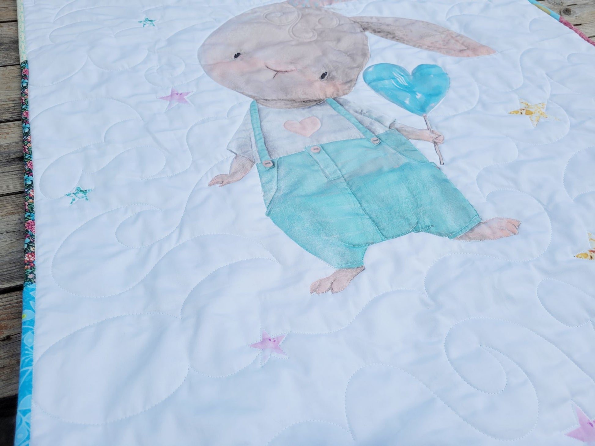 Quilt with a bunny character holding a blue heart balloon on a white background