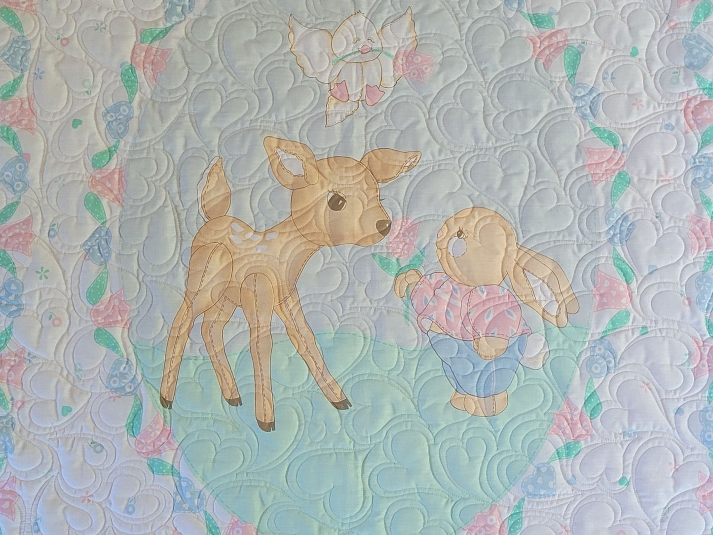 Quilt with a deer and bunny design on a patterned background.