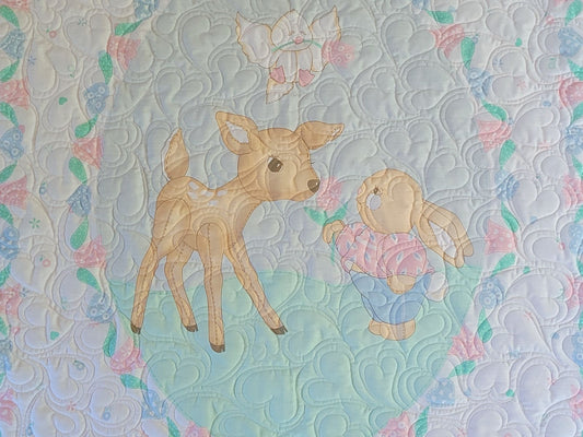 Quilt with a deer and bunny design on a patterned background.