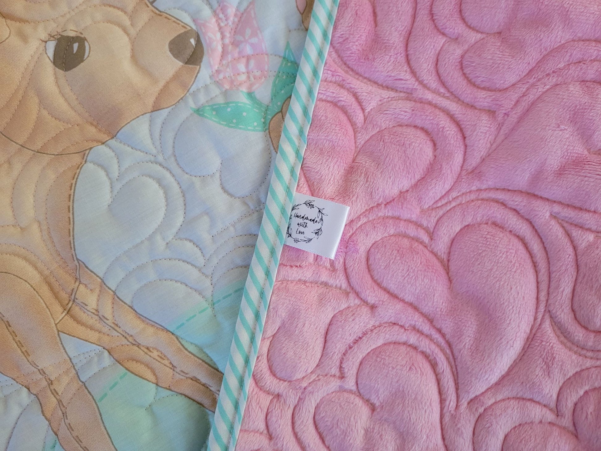 Baby quilt showing a close up of the pink minky backing and handmade with love label.