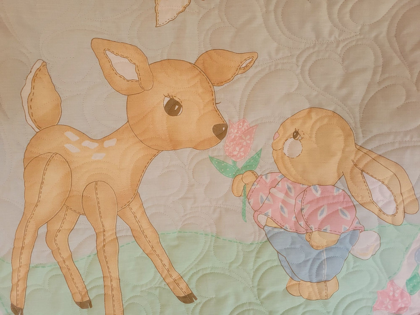 Close up of quilt showing the fawn and baby rabbit holding a flower.