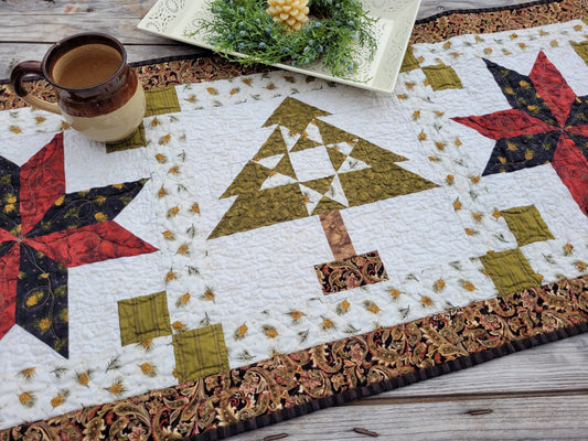 Quilted Christmas table runner on a weathered wooden table styled with a pottery mug and decorative tray.