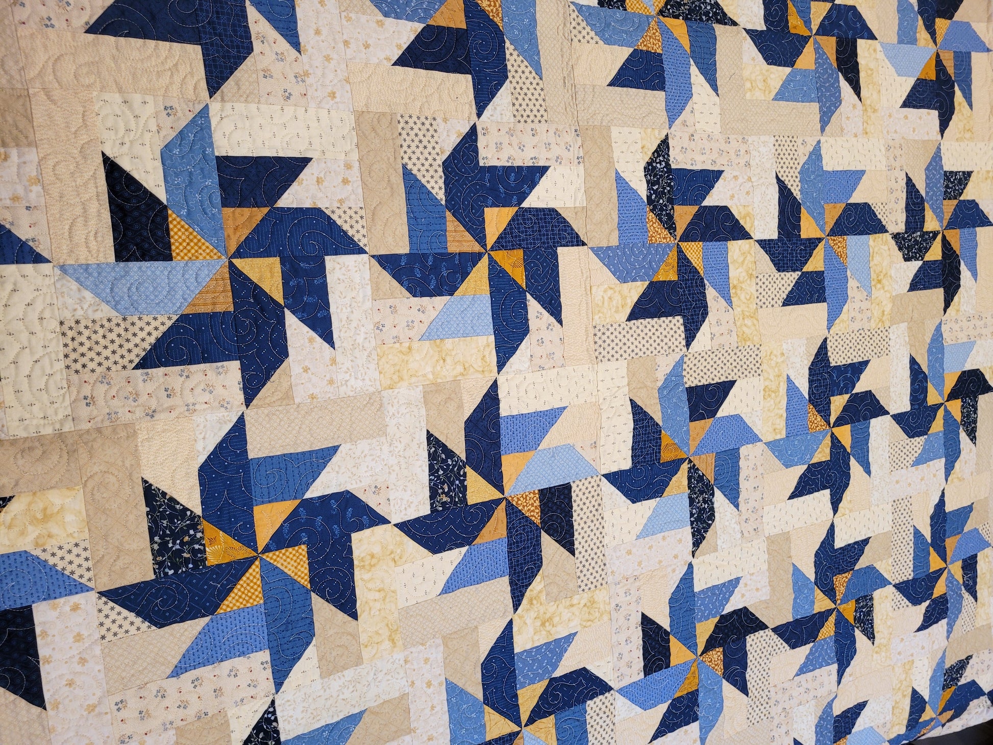 scrappy pinwheels in blue, cream with gold accent on king size bed quilt