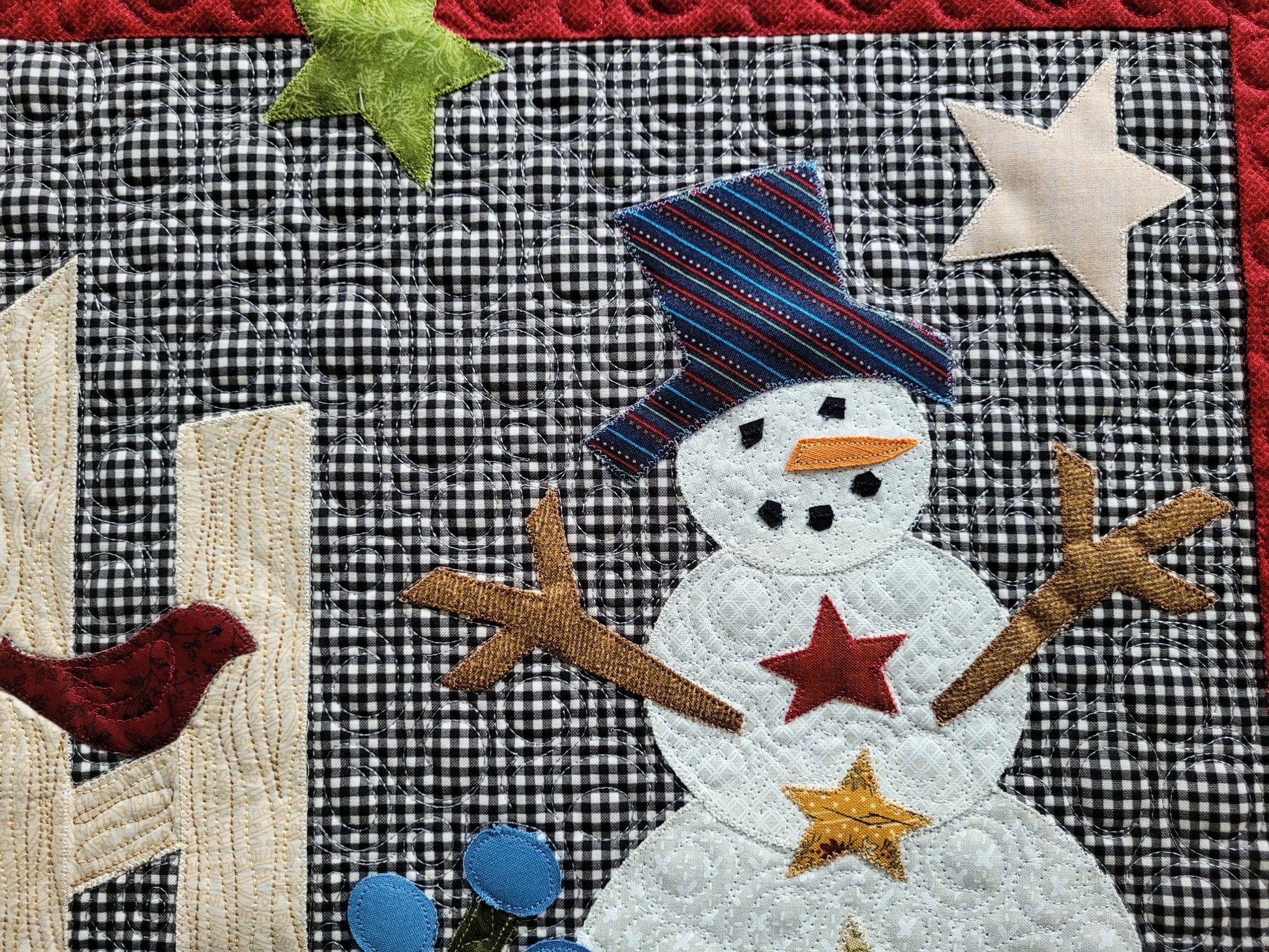 Showing close up detail and custom stitching of applique snowman on gingham background.