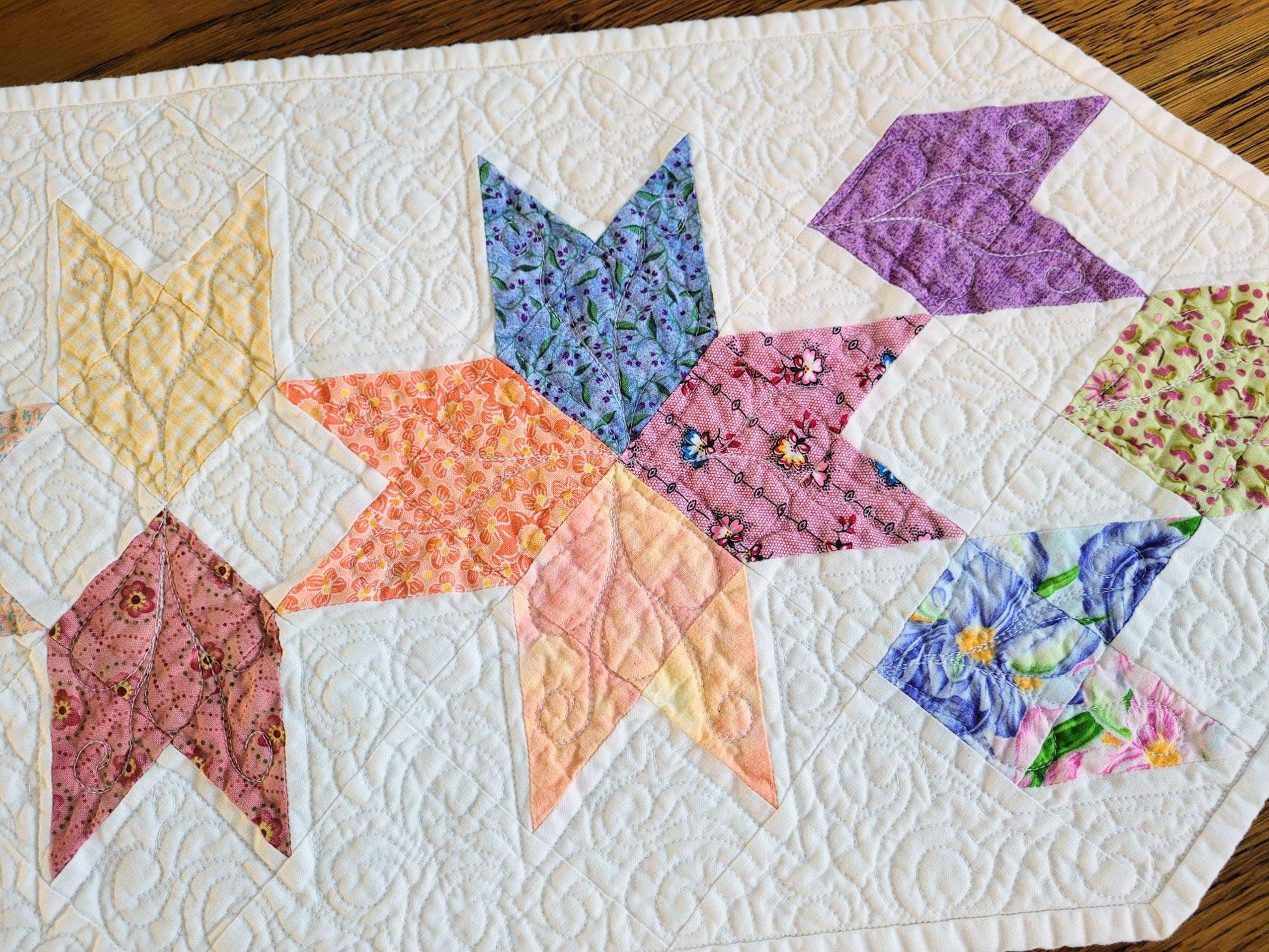 Close up of pastel tulip patchwork showing custom freemotion quilting used on the table runner.