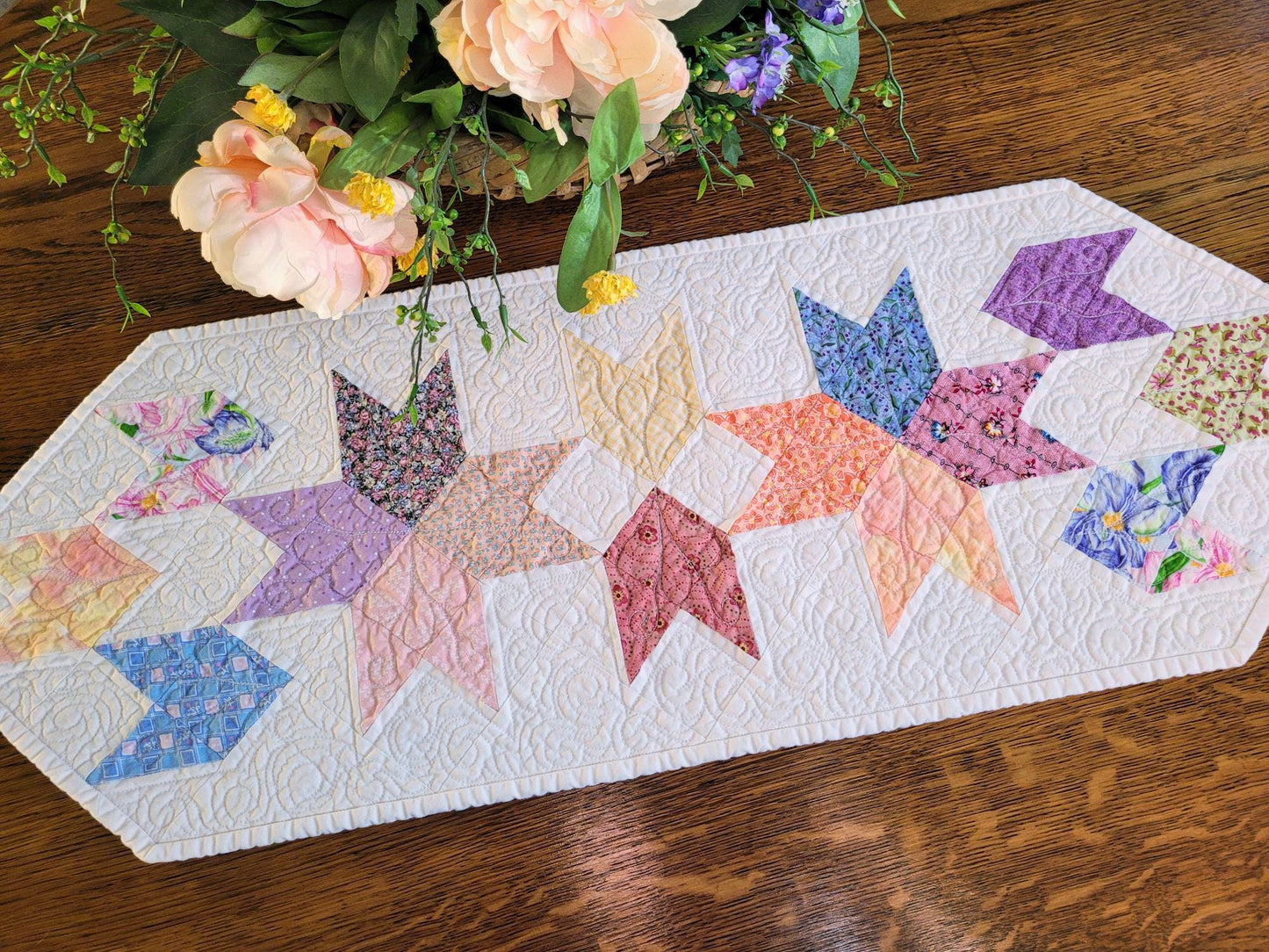 Spring tulip runner in pastel colours on white background on wood surface.
