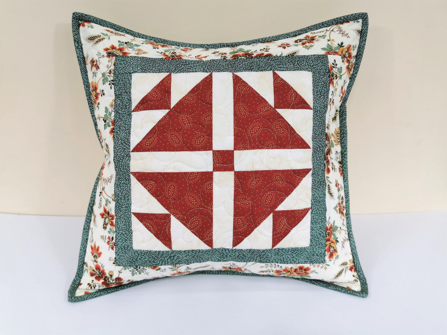This quilted throw pillow has striking red and white patchwork in the center set off by a teal border. The pretty floral border that finishes the pillow mirrors the teal and red patchwork for a beautiful coordinated look.