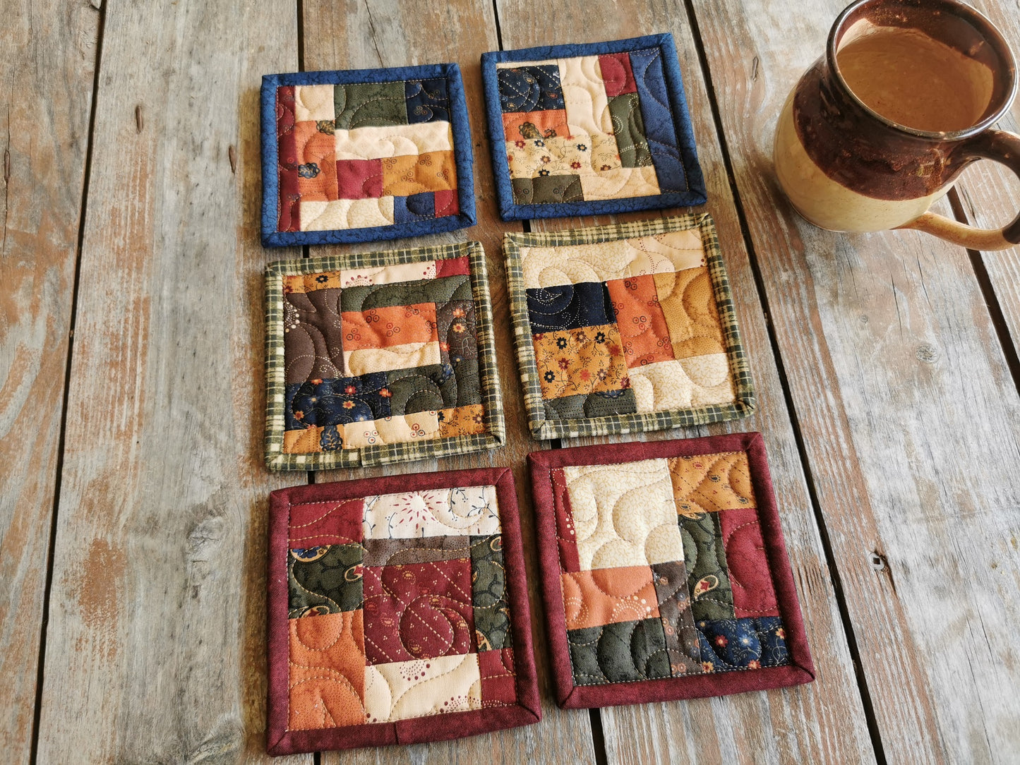 These quilted fabric coasters are done in scrappy patchwork style and rustic country colors.