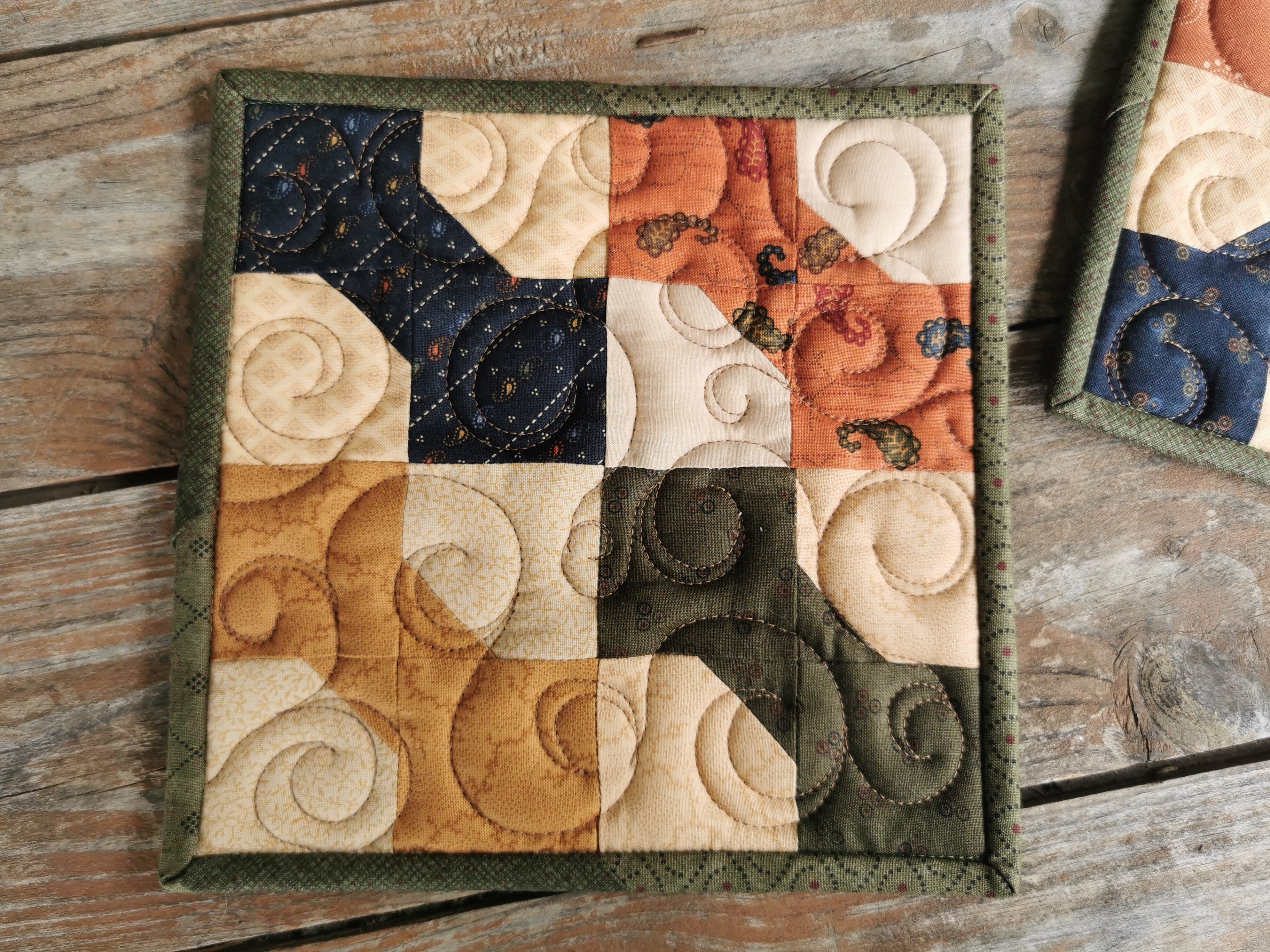 This is a close up of one of the quilted potholders showing the bowtie patchwork, fabric designs and swirl quilting.