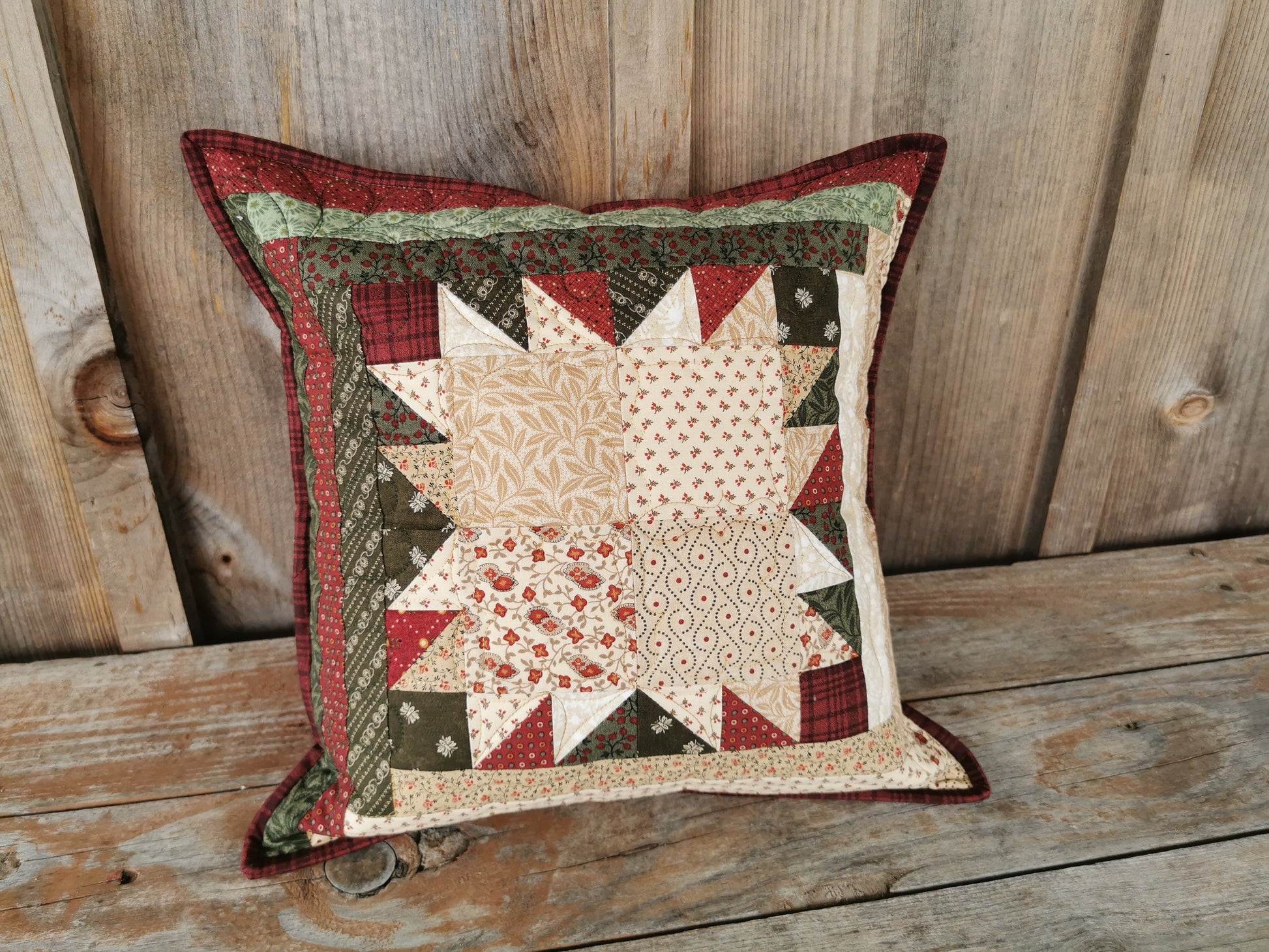 This scrappy patchwork pillow is done in the bear paw pattern. A traditional Christmas colours of red, green and cream make this suitable for holiday decor.  