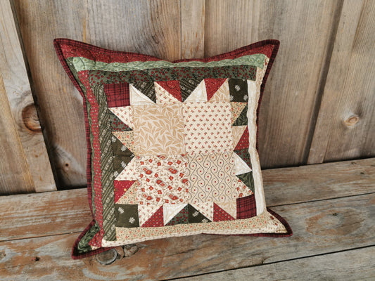 This scrappy patchwork pillow is done in the bear paw pattern. A traditional Christmas colours of red, green and cream make this suitable for holiday decor.