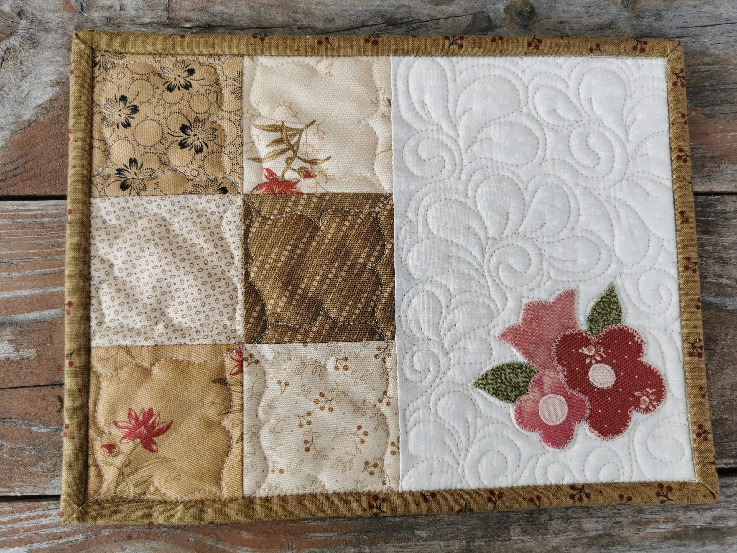 The flower mug rug is shown in a close up view to see the  applique flowers and custom quilting