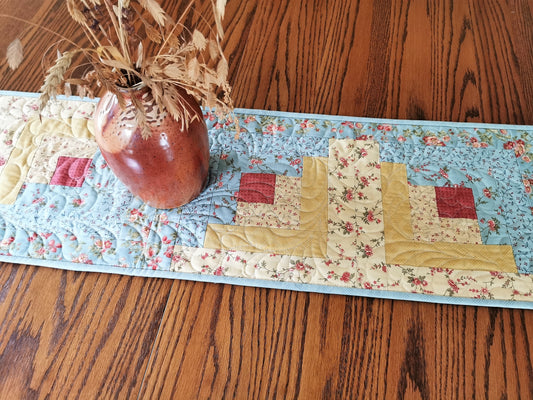 This pretty floral log cabin table runner is done in a soft teal blues and golden yellows with a touch of coral pink. Very pretty.