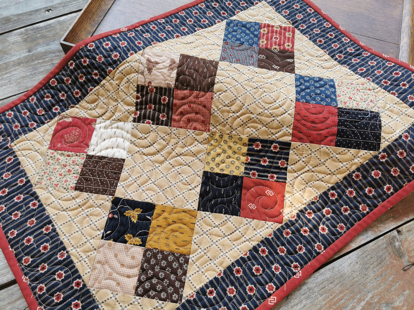 The quilted table runner is pictured on a slight angle to showcase the swirl quilting , which adds nice texture. Scrappy fabrics are civil war reproduction prints.