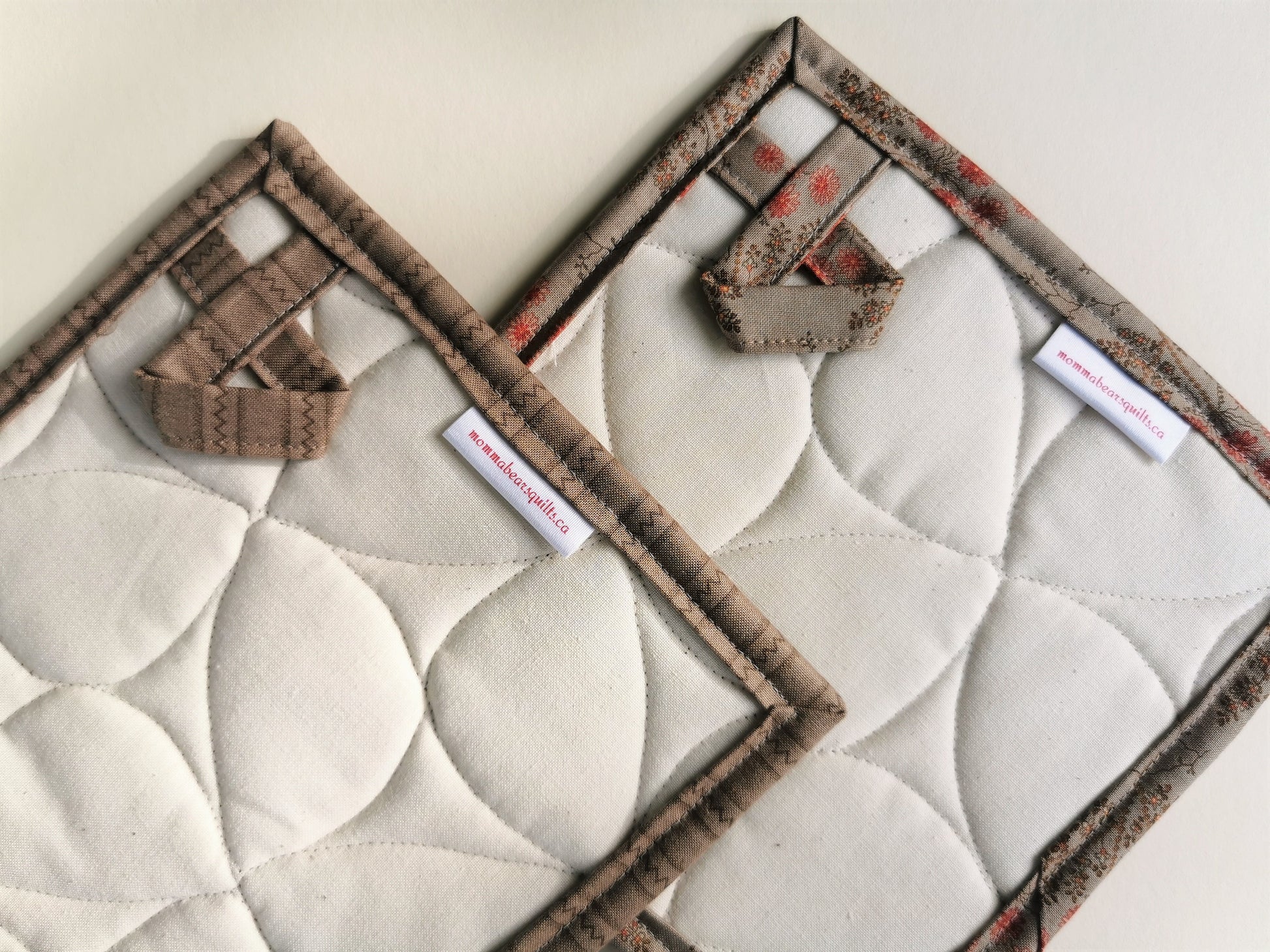 the quilted patchwork potholders back view is showing the hanging loops and the stitching texture.