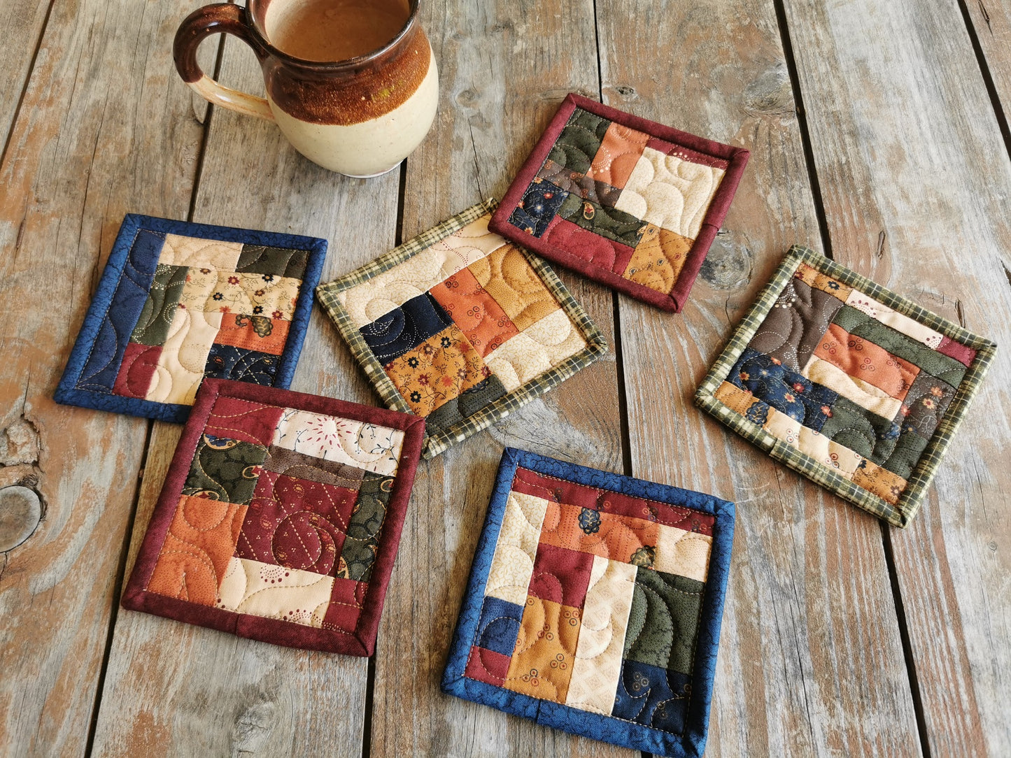 six rustic fabric coasters are quilted and bound in three different color sets so that you receive two each of green, blue and red.
